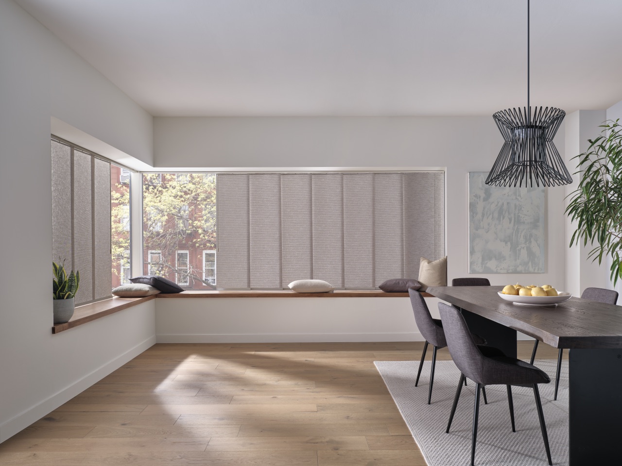 Skyline® Gliding Window Panels spanning a wide living-room window wall with soft gray textured panels and built-in bench seating