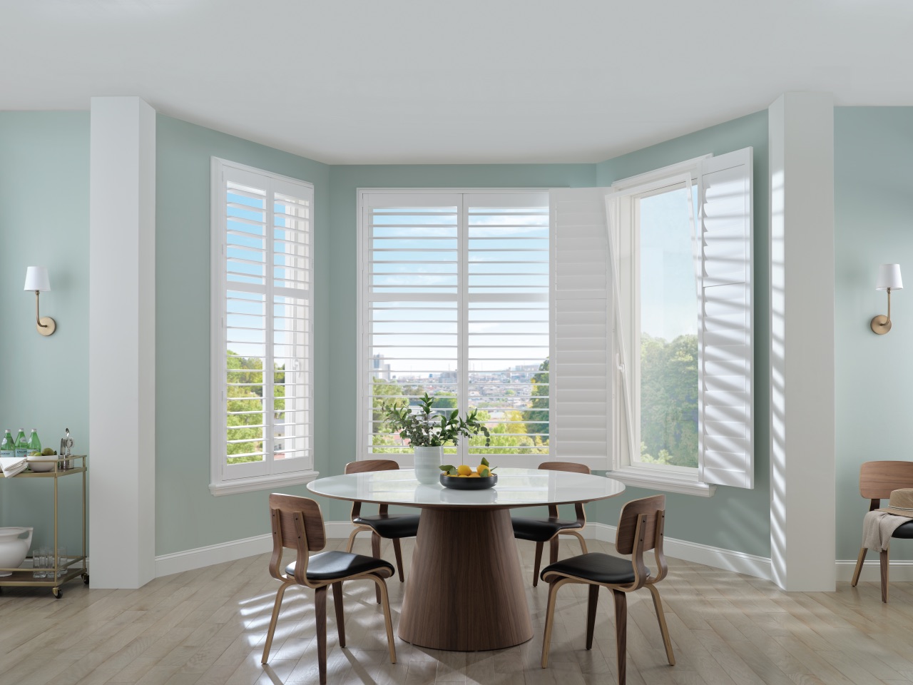 Palm Beach™ Polysatin™ Shutters in a bright bay-window dining room with pale blue walls and soft daylight